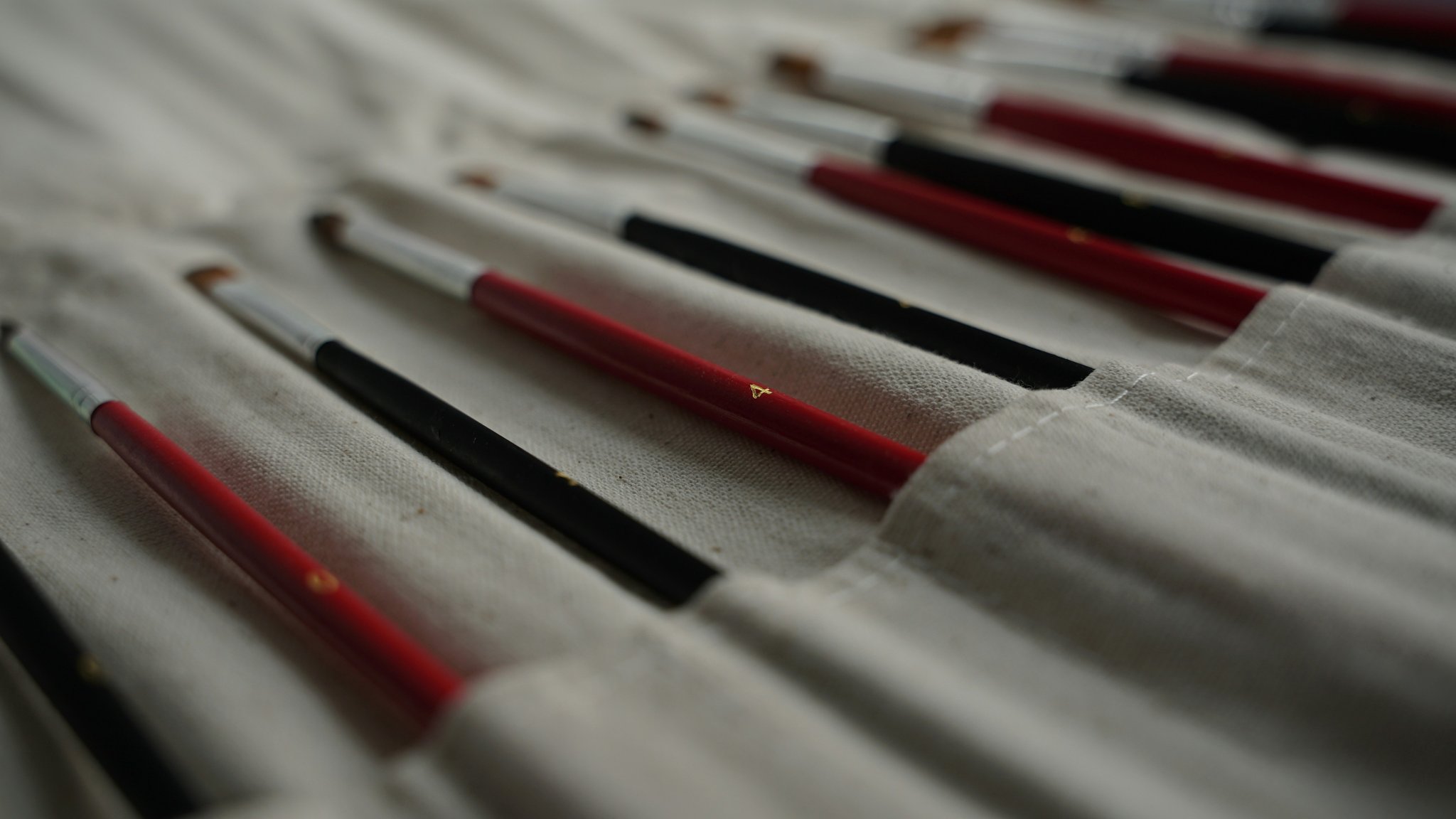 A close-up image showing various nail art brushes being used to paint detailed patterns on nails.