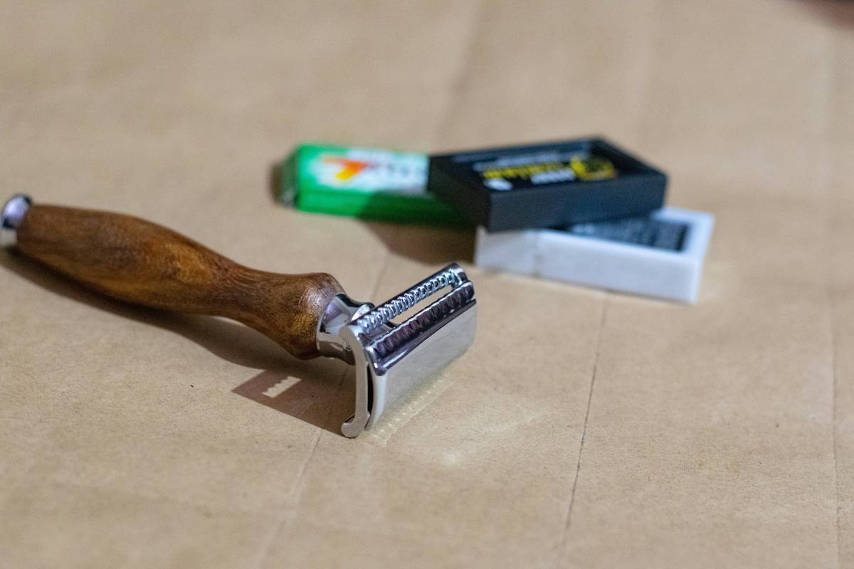 A close-up shot of a silver premium nail stamper sitting on a white surface next to nail polish bottles.