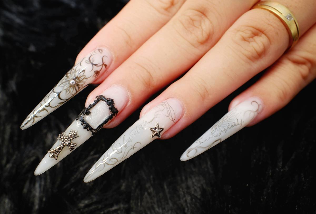 A hand with long, pointed, intricately decorated nails.