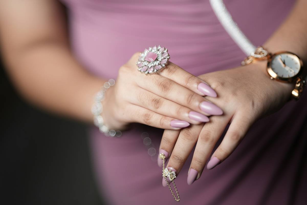 A woman in a purple dress holding a ring and a watch