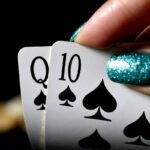 Someone with nail varnish taking a look at their playing cards. Looks like they have a good hand.
