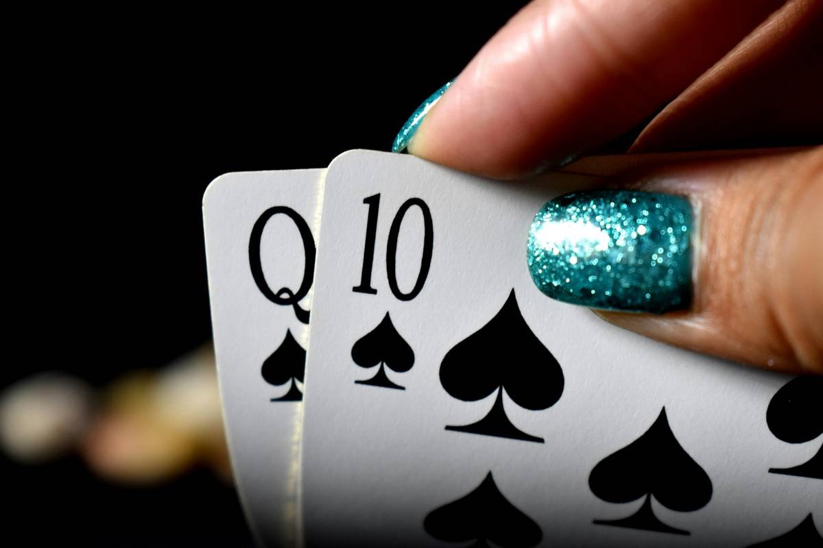 Someone with nail varnish taking a look at their playing cards. Looks like they have a good hand.